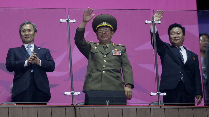 North Korea's National Defense Commission Vice Chairman Hwang Pyong So, middle, waves as the country's athletes march at the end of the Asian Games. He's flanked by Workers Party Secretary Choe Ryong Hae, right, and South Korea's Kim Kwan-jin, left, national security adviser to South Korea's president.