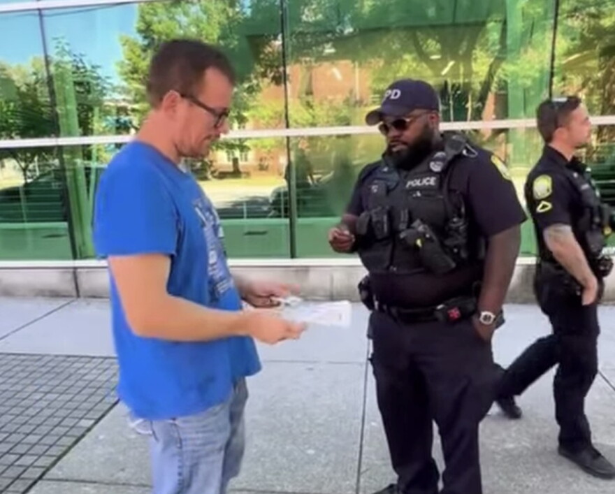 Matt Cox (blue shirt) receives a citation for alleged sidewalk obstruction by police officers with the City of Columbia Police Department on September 26, 2026.