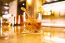 This is a close-up image of a glass of whiskey on a bar top. 