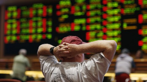 A man watches a baseball game in a casino.