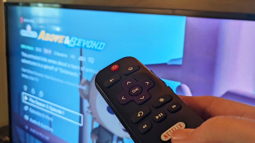 person holding a remote in front of a tv