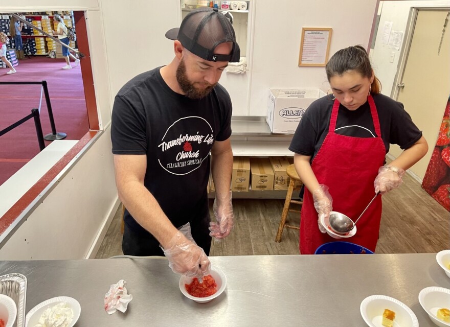 Kyle Judah, left, the pastor of Transforming Life Church in Plant City, works with a volunteer at the church’s booth at the Florida Strawberry Festival to make about 2,600 servings of strawberry shortcake each day.