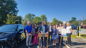 Colonie Town Supervisor Peter Crummey celebrates the unveiling of a new electric vehicle charging station and new electric town vehicle at the William K. Sanford Library on August 27th, 2024.