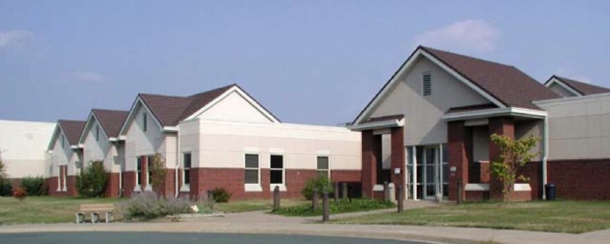 A photo of the Commonwealth Center for Children and Adolescents in Staunton, VA. A maroon and tan building with a gable roof against a blue sky. 