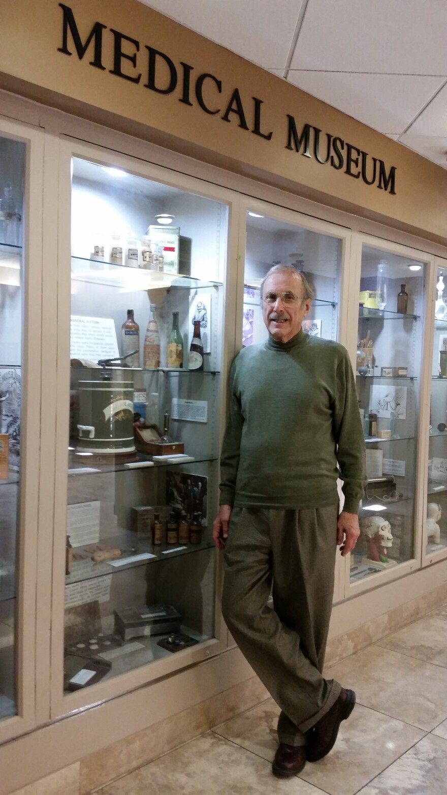 Dr. Robert Kravetz, who teaches at UofA College of Medicine and practices at Phoenix Baptist Hospital, poses in front of several of his many medical artifacts on display at the hospital. He's collected medical and pharmaceutical items for several decades.
