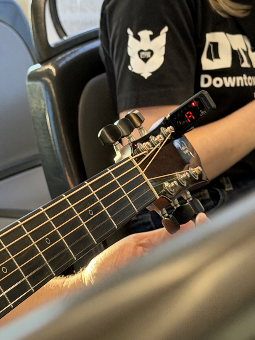 Person adjusting knobs on a guitar neck