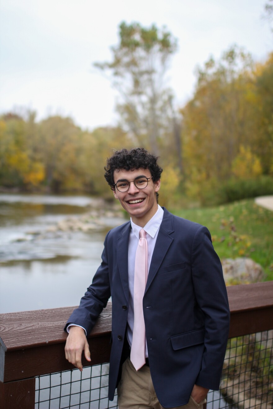 Jacob Toomey smiles while standing in front of a river.