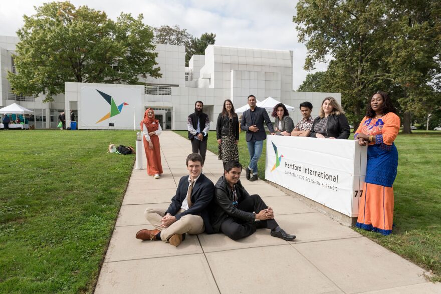 Hartford International University peacebuilding students in front of the new sign in front