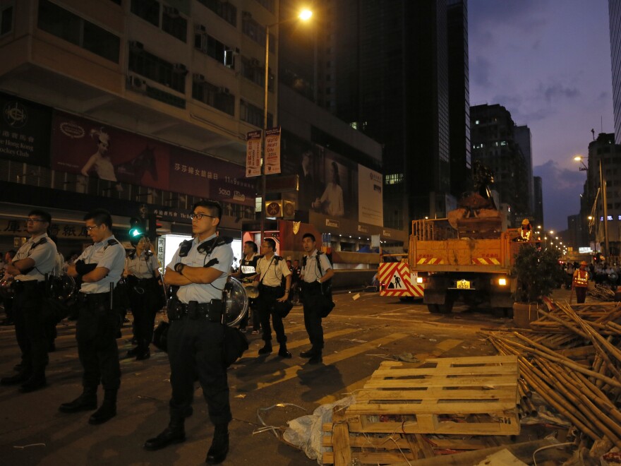 Police officers stand guard at a main street in Mong Kok district in Hong Kong on Friday, where they raided a student protest site.