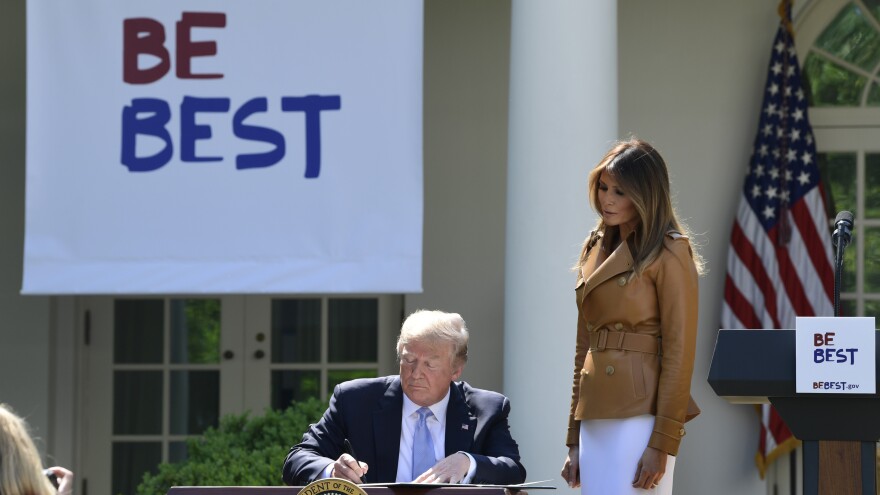 President Donald Trump signs a proclamation as first lady Melania Trump watches during an event where the first lady announced her initiatives in the Rose Garden of the White House Monday.
