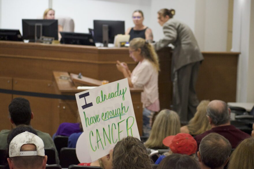 A resident speaks during Monday’s North Port City Commission meeting as a sign opposing data centers rests nearby.