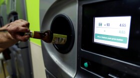 A person recycles a glass beverage bottle at an automated reclamation machine