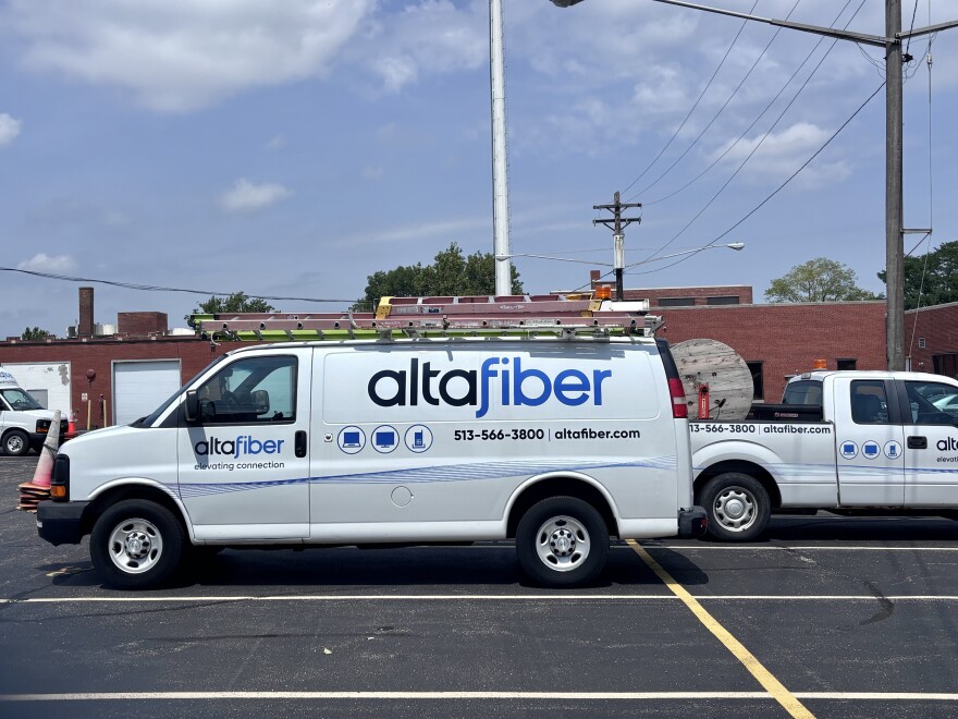 A white truck with safety cones on the front and a ladder on the roof sits in a parking lot. It has a blue Altafiber logo.