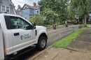 A Duke Energy truck parked on a residential street. In the background, a tree branch lays on sagging power lines.