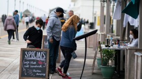 A woman uses a face mask as she sells drinks at a bar by the boardwalk  in Asbury Park, New Jersey on May 24, 2020 getting started on the Memorial Day weekend holiday. (Kena Betancur/AFP via Getty Images)