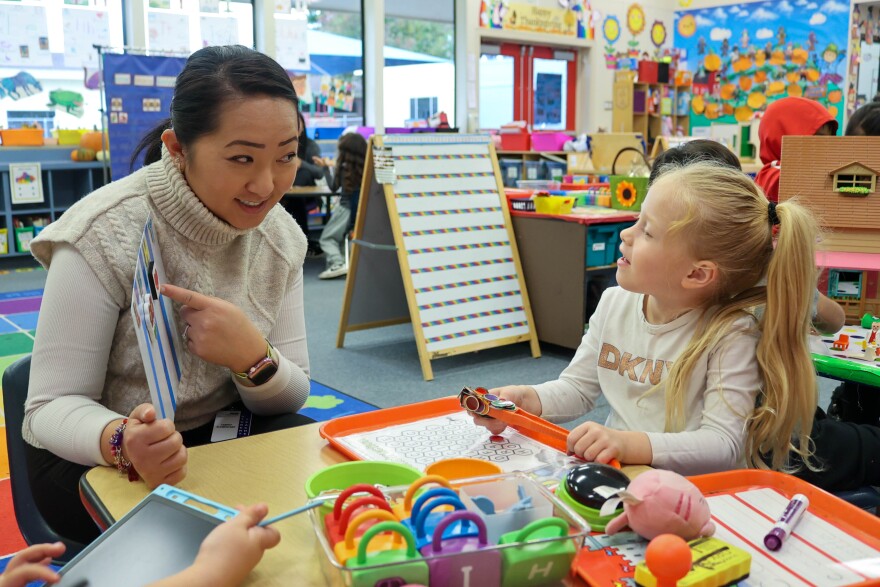 Student teacher Yer Yang points to a picture of a horse as she asks one student to sound out the word.