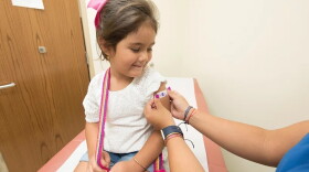 A doctor placing a bandage on the injection site of a child. 