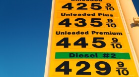 High gas prices on yellow sign over blue sky.