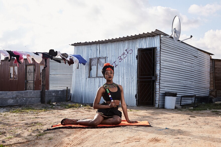 Mthulic Vee Vuma, a 21-year-old studying public management at West Coast College, wears traditional Xhosa clothing and jewelry in front of a shack in Khayelitsha. "The meaning of the clothing I am wearing is to love and accept our culture," Vuma says. Her family initially struggled to accept her as a trans woman, believing it was a curse, but she says they now give her total support.