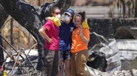 Women hug after digging through rubble of a home destroyed by a wildfire on Friday, Aug. 11, 2023, in Lāhaina, Hawaii.