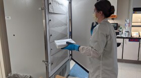 A worker at Providence Medford loads a shipment of the new COVID-19 vaccine into a freezer for storage.