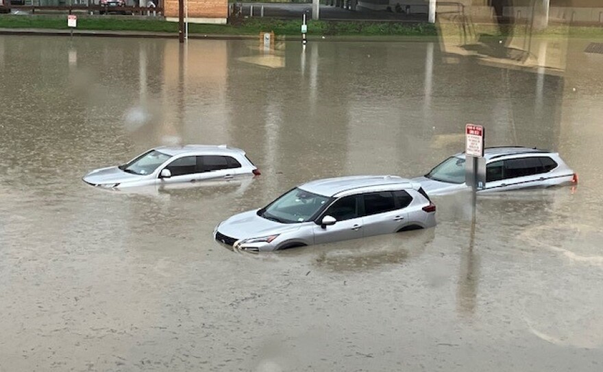 Three vehicles are submerged in water in a parking lot