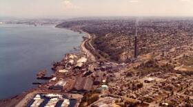 An image of the ASARCO smelter in Tacoma, showing the smokestack rising above the waterfront. Photo credit Tacoma Public Library.