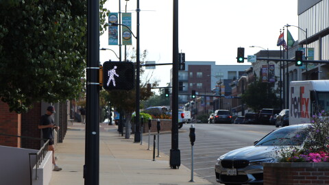 A traffic sign shows the white light walk man for pedestrians to cross. A street in downtown Columbia is in the background.