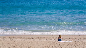 A woman sits on the beach in Stuart, Florida on a sunny Summer morning