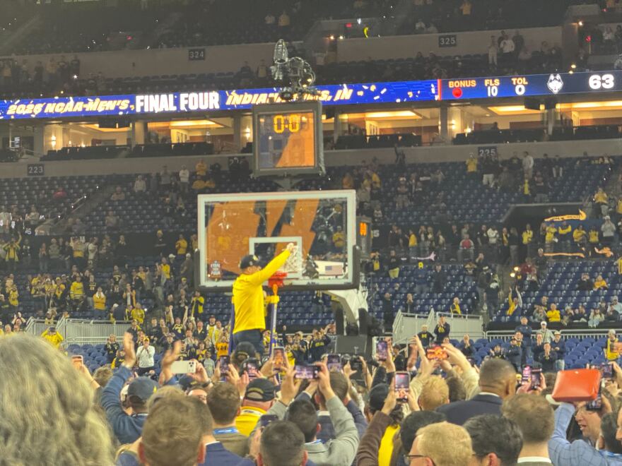Head Coach Dusty May cuts down the net after Michigan wins.