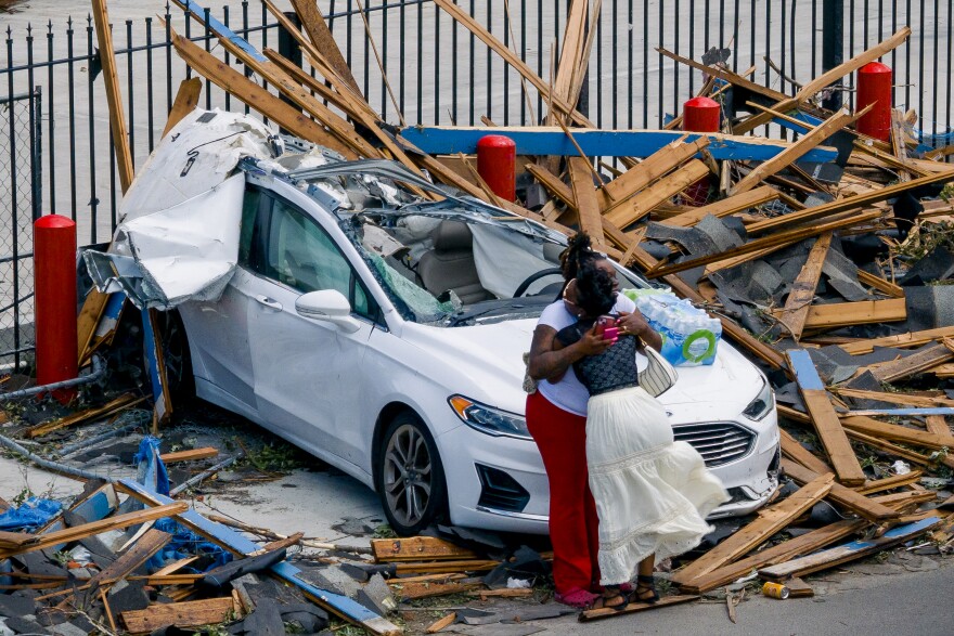 Victoria Cooper, 36, hugs a volunteer near her wrecked car on Natural Bridge Ave on Saturday, May 17, 2025, in north St. Louis. She and her 15-year-old son Pa'den McCulley were in the car when the storm hit. Cooper said they climbed out the broken windshield and took shelter in a nearby Boost Mobile.