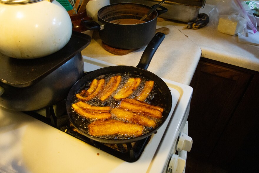 English: A photo of a stovetop with a cast iron pan on a burner, with slices of plantain frying in bubbling oil. Español: Una foto de una estufa con una sartén de hierro sobre un quemador, con rodajas de plátano friéndose en aceite burbujeante.