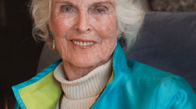 Portrait of Harriet Bullitt with white hari and turquoise jacket with collar turned up.