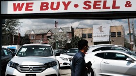 A man walks by a New York City auto dealership in 2017. Studies have found that African-Americans and Hispanics have systematically been charged a higher markup on auto loans than have white borrowers.