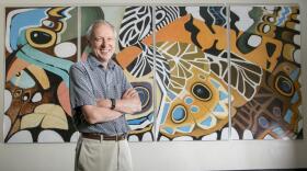 Fred Nijhout poses with crossed arms in front of abstract 