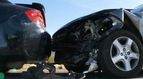 Two cars that appear to have been in a fender bender are hood-to-trunk on a road.