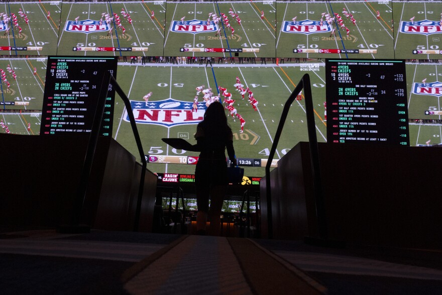 A waitress carries an order as fans watch the Super Bowl 58 NFL football game on screens at a sportsbook, Sunday, Feb. 11, 2024, in Las Vegas. (AP Photo/Gregory Bull)