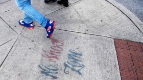 Two men walk past a sign spray painted on the sidewalk stating "No Shoot Zone" in Baltimore, Maryland, on Dec. 17, 2018. (Jim Watson/AFP/Getty Images) 