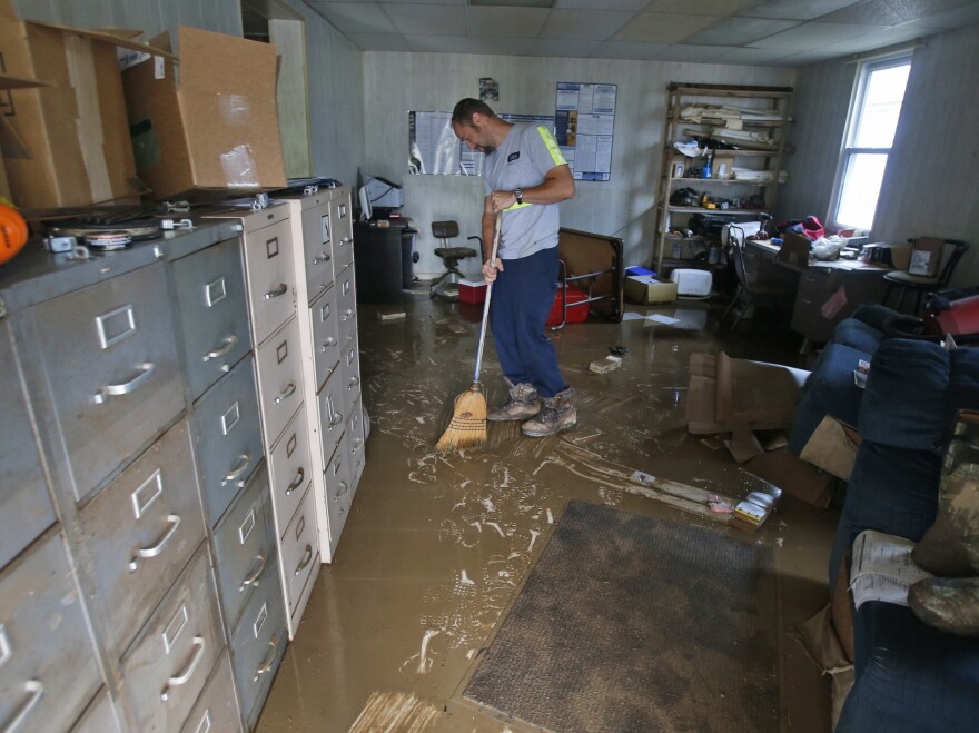 Shane Altzier sweeps out the mud from the utilities office in Rainelle, W.Va., one of the towns hardest hit by floods that tore through the state on Friday. More rain this week has slowed cleanup efforts.