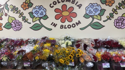 A flower display under a sign of a red flower surrounded by the words "Columbia in Bloom"