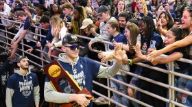 Freshman center Donovan Clingan carries the NCAA championship trophy and greets fans as the the UConn men’s basketball team returned to Gampel Pavilion on April 4, 2023, after winning the NCAA championship in Houston.