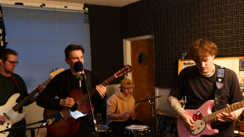 Four people play in a band in a small corner. 