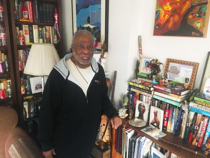 A man stands in his apartment near books