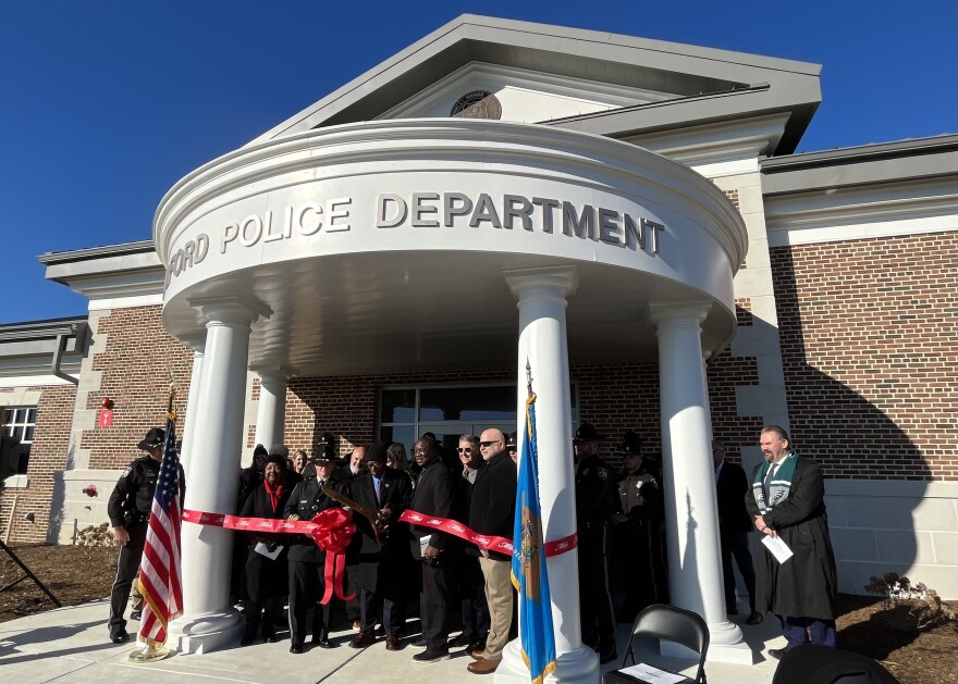 Milton Mayor Arthur Campbell cuts the ribbon to announce the opening of the city's new police department alongside Milton police officers, city council members and esteemed community members on Tuesday.