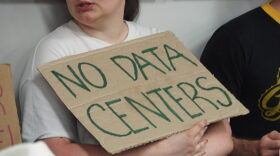 An audience member attending a Pulaski County Quorum Court agenda-setting meeting holds a sign opposing data centers on June 9, 2026.