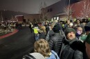 People in coats and hats stand outside on a cold, dark night in Park City, Utah.