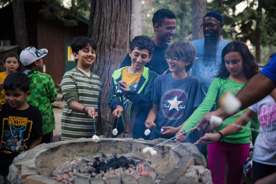 Campers roast halal marshmallows to make s'mores.