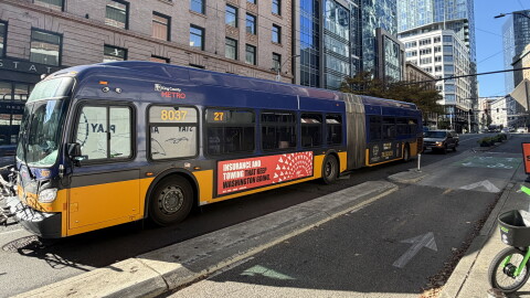 A photo of a yellow and purple King County Metro bus in downtown Seattle. 