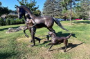 Statue of a girl walking a horse alongside a running dog.