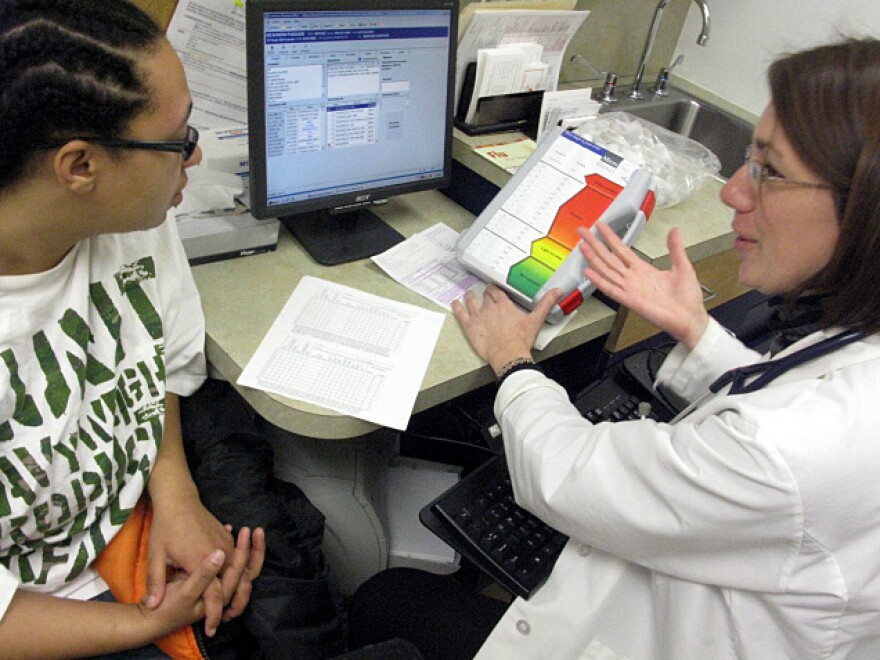 Sondra Pasquine, 24, talks with her smoking cessation counselor, Allison Diamond, at a community health center in Boston. Diamond shows Pasquine a chart on toxic carbon monoxide levels in smokers' lungs.